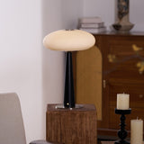 LED table lamp lit on a plinth with stacked books on the cabinet behind