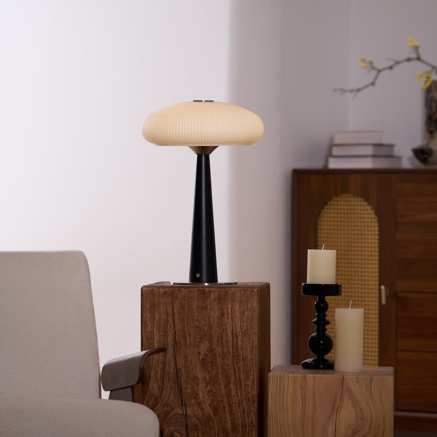 LED table lamp lit on a plinth with a bare branch in a vase behind