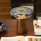 LED table lamp with the smoked glass disc lit on a wooden desk
