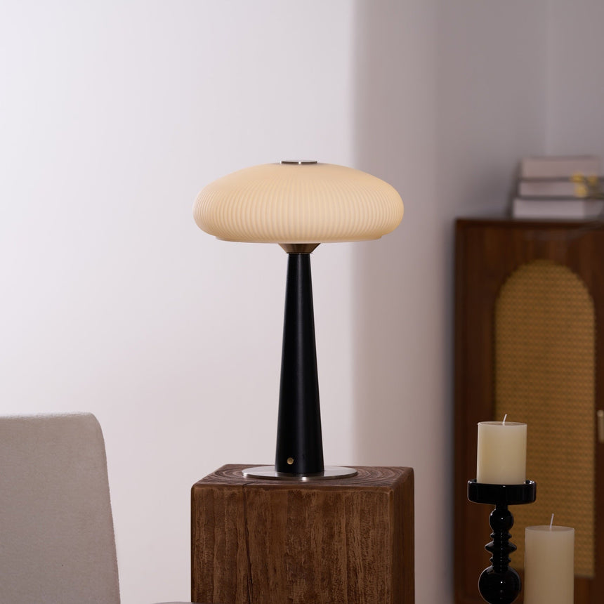 LED table lamp unlit on a wooden plinth beside a pillar candle