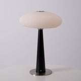 LED table lamp lit in a warm tone on a wooden plinth in a pale room