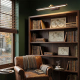 Brass bar lit above a bookcase of old books beside an armchair and a side table