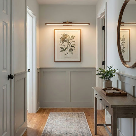 Walnut tone bar lit above a framed print in a hallway with a console and a mirror