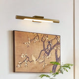 Brass tube lit over a large framed painting of blossom on a pale wall