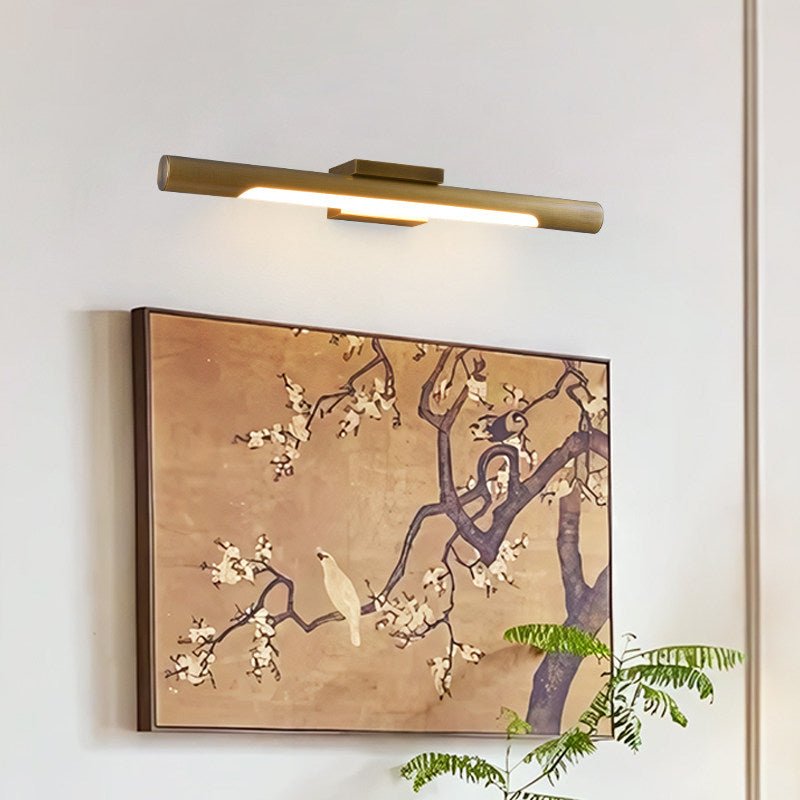 Brass tube lit over a large framed painting of blossom on a pale wall