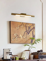 Brass tube lit over a framed painting above a counter with a coffee maker