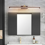 Walnut tone bar lit above a framed mirror on a stone wall over a white basin