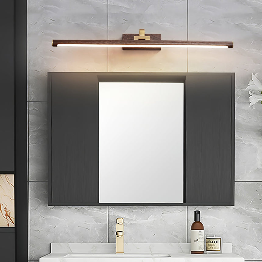 Walnut tone bar lit above a framed mirror on a stone wall over a white basin