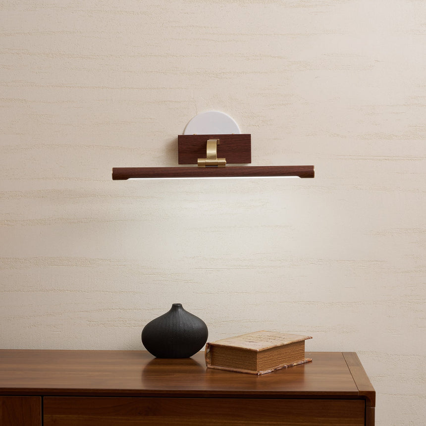 Walnut tone bar lit above a wood cabinet with books and a small black vase
