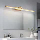 Brass bar lit above a wide mirror over a double basin with a plant and towels