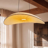 The lit shade beside pale curtains under an exposed wood ceiling beam