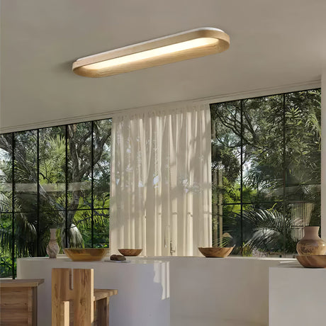 Linear wood frame ceiling light lit in a room with tall windows and sheer curtains