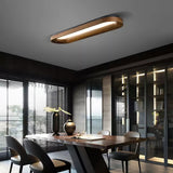 Linear wood frame ceiling light above a dining table beside a glazed wall