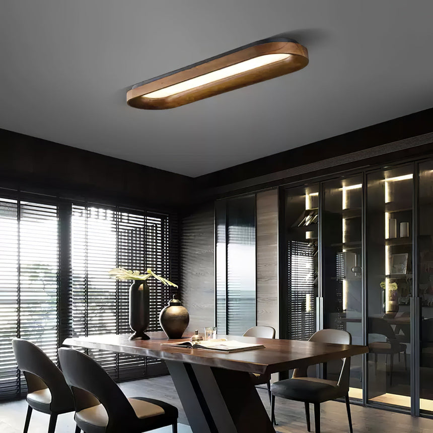 Linear wood frame ceiling light above a dining table beside a glazed wall