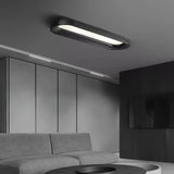 Black linear ceiling light in a gray room with a low sofa and a panelled wall