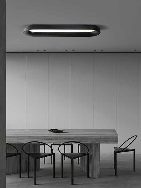 Black linear ceiling light above a long dining table with wire chairs