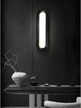 Linear ceiling light mounted vertically on a dark wall above a console