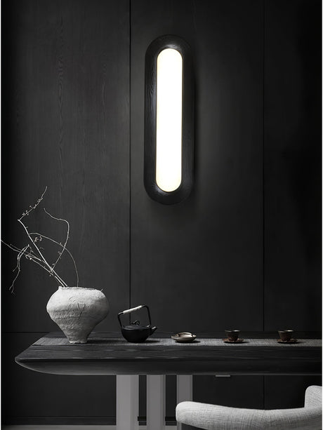 Linear ceiling light mounted vertically on a dark wall above a console