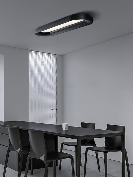 Black linear ceiling light above a dark dining table in a pale room