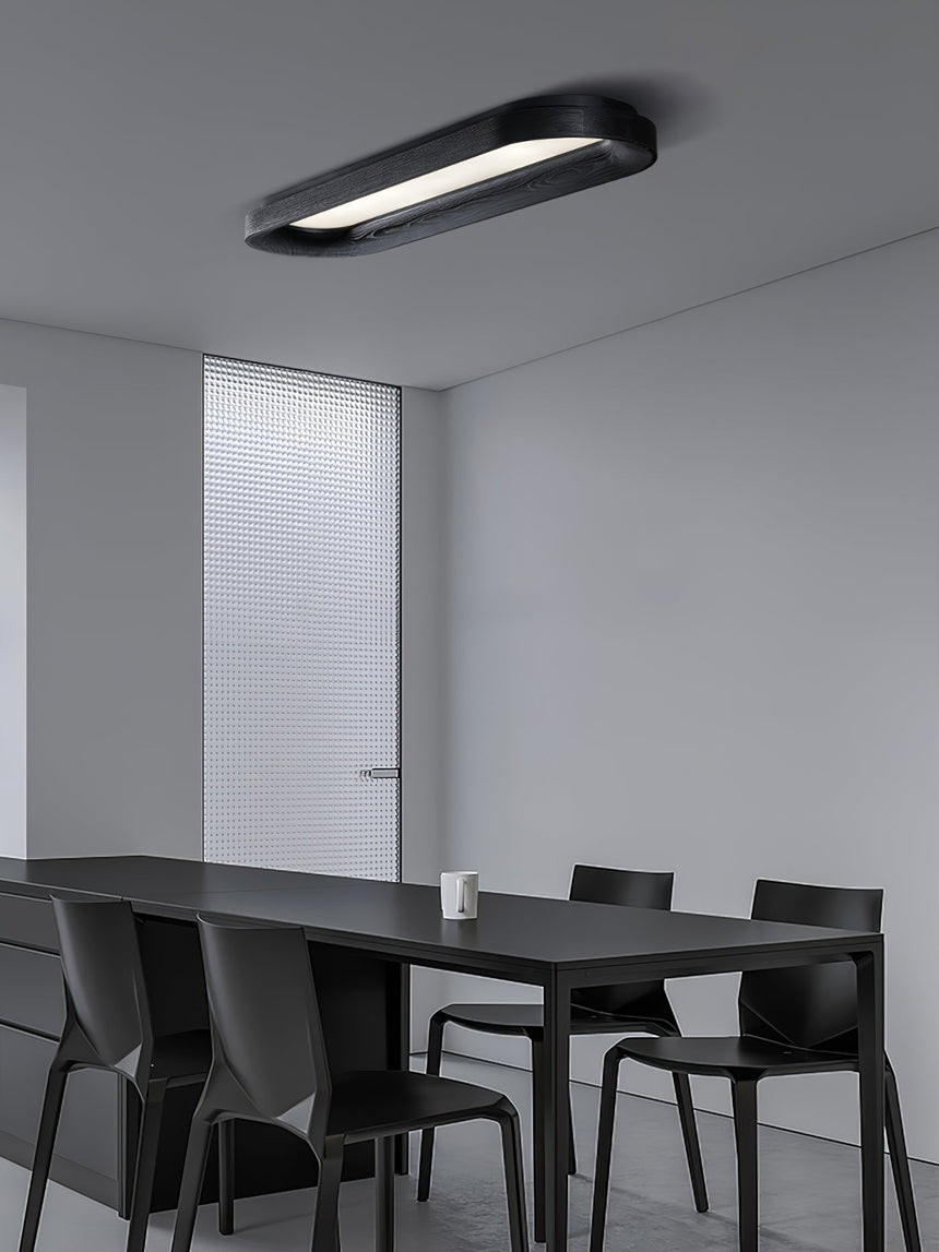 Black linear ceiling light above a dark dining table in a pale room