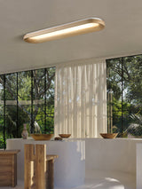 Linear wood frame ceiling light lit near tall windows and a wooden counter