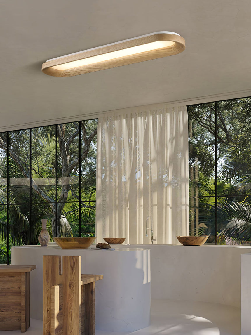 Linear wood frame ceiling light lit near tall windows and a wooden counter