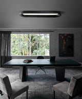 Black linear ceiling light above a dark meeting table with armchairs