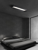 Black linear ceiling light lit above a low bed in a gray bedroom