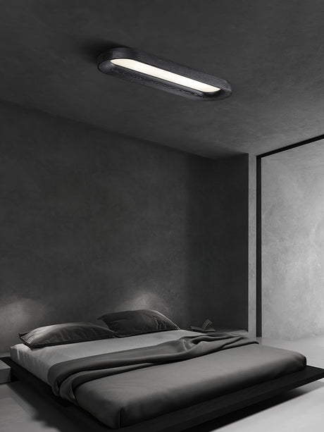 Black linear ceiling light lit above a low bed in a gray bedroom