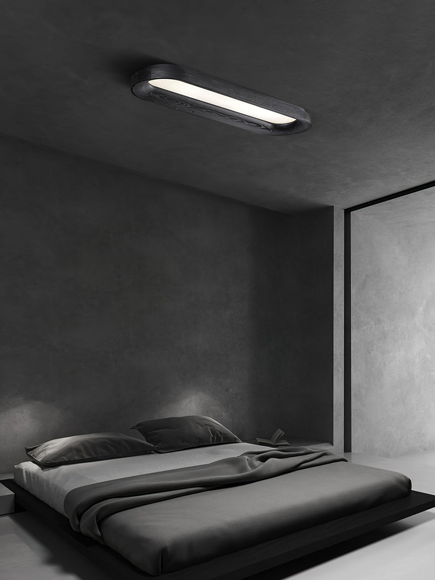 Black linear ceiling light lit above a low bed in a gray bedroom