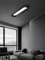 Black linear ceiling light in a living room with a window and a gray sofa