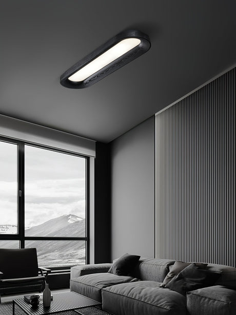 Black linear ceiling light in a living room with a window and a gray sofa