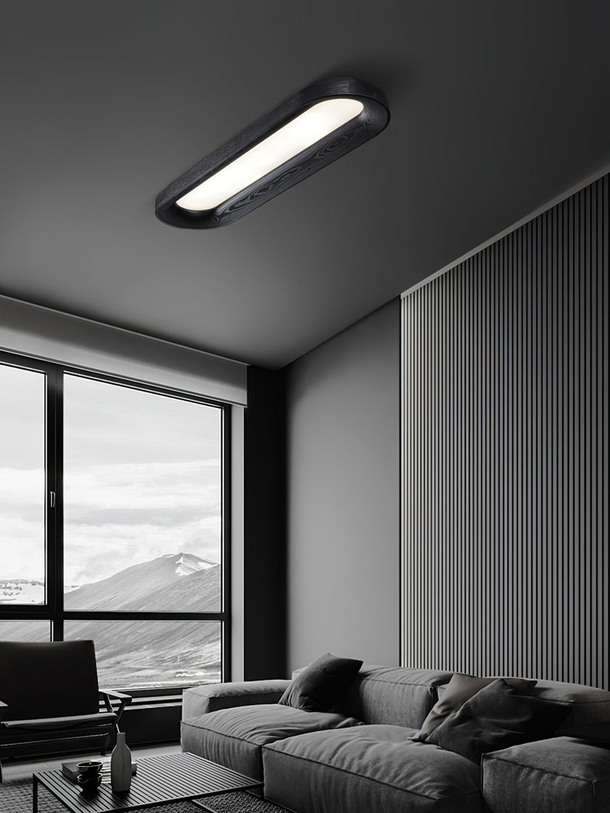Black linear ceiling light in a living room with a window and a gray sofa