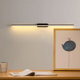 Thin rod lit above a wood surface with a framed print, a cup and a book