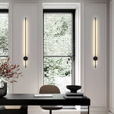 A pair lit either side of a window above a dark desk with a vase and a chair