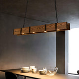Lit above a dining table with stacked plates and a glass bowl against a dark wall