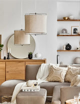 Linen drum pendant light lit in a furnished living room