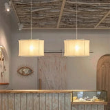 Two linen drum pendant lights hung in a row above a counter