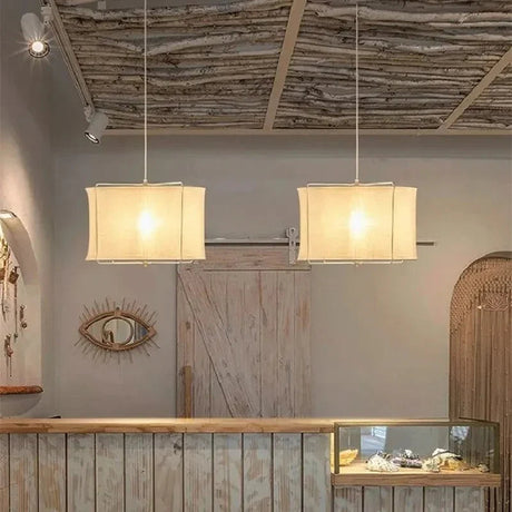 Two linen drum pendant lights hung in a row above a counter
