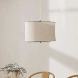 Linen drum pendant light lit against a plain pale wall