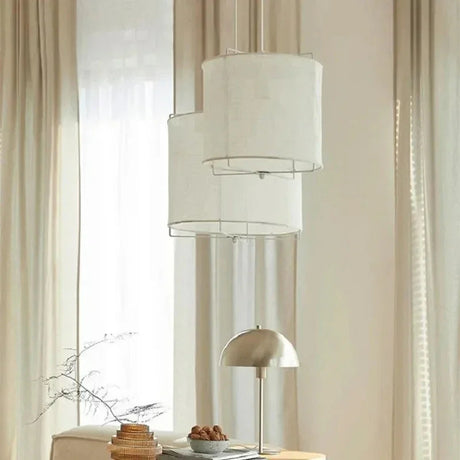 Linen drum pendant light hung in front of a tall curtained window