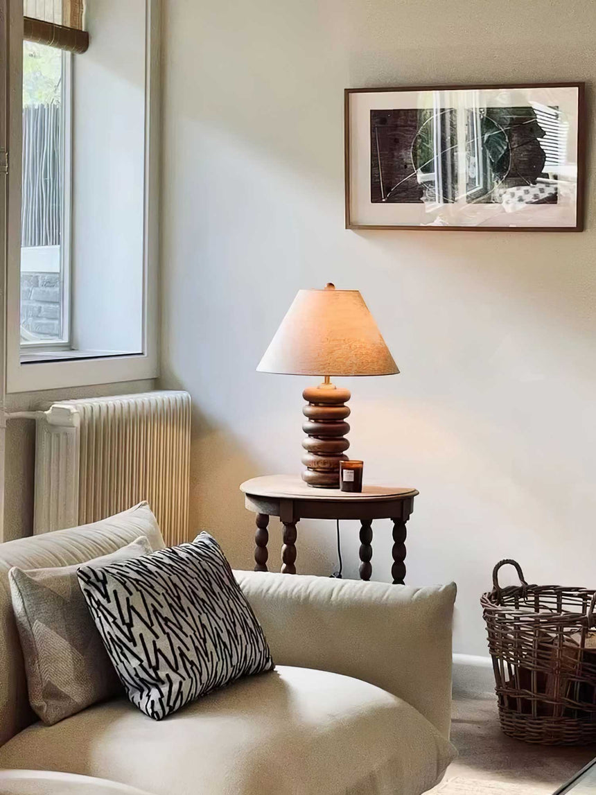 Linen shade table lamp lit on a side table in a reading corner