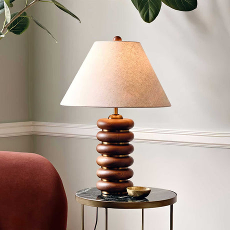 Linen shade table lamp on a round side table beside a plant