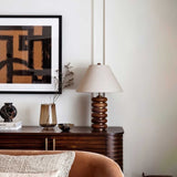 Linen shade table lamp on a sideboard below a framed artwork