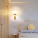 Sconce lit in a bedroom nook above a bed with a round cushion and a stool