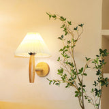 Sconce lit on a warm wall beside a tall green plant in a bright corner