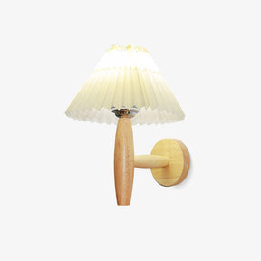 Linen wall sconce with a pleated white shade on an oak arm and a brass plate
