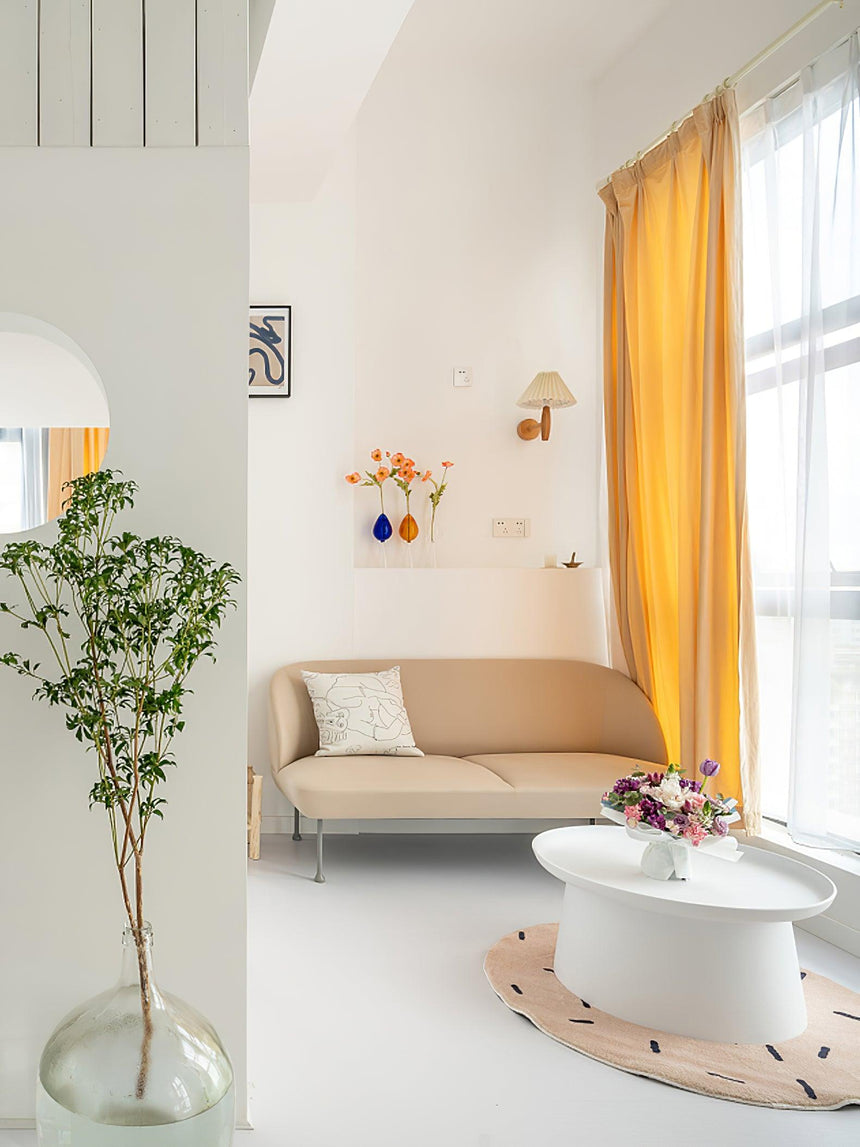 Sconce on a living room wall above a sofa beside a window with a curtain