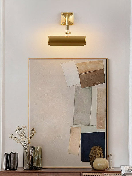 Brass tube lit over a framed artwork above a console with vases and stones