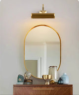 Brass tube above an arched mirror on a walnut dresser with glassware